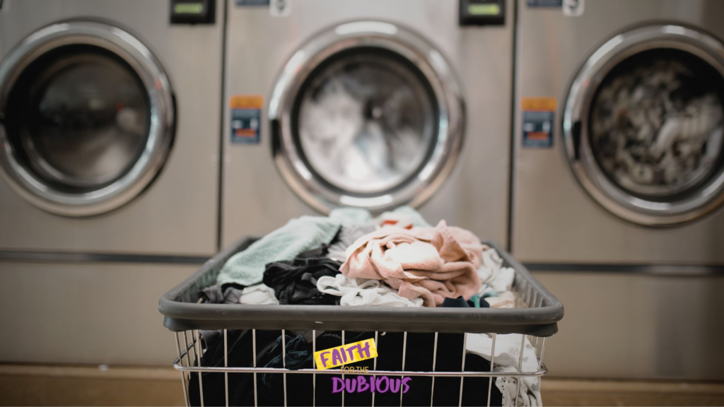 A rolling basket in front of a commercial washing machine at a community laundry day.